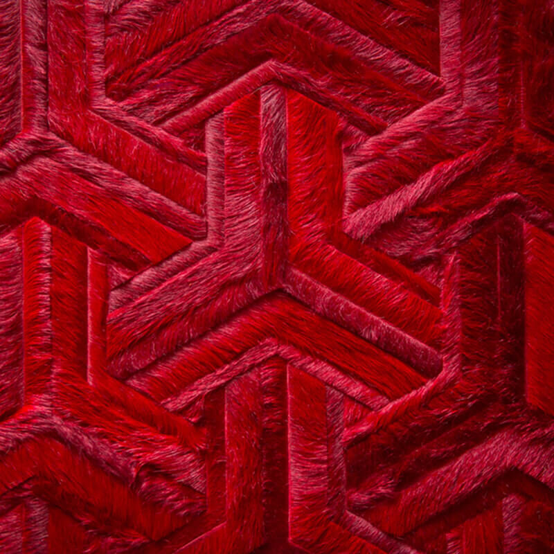 Close-up of luxury designer rug featuring red chevron pattern and plush, high-end wool texture.