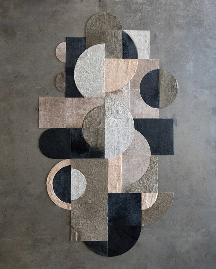 Luxury designer rug with geometric circles and rectangles in neutral tones on concrete floor.