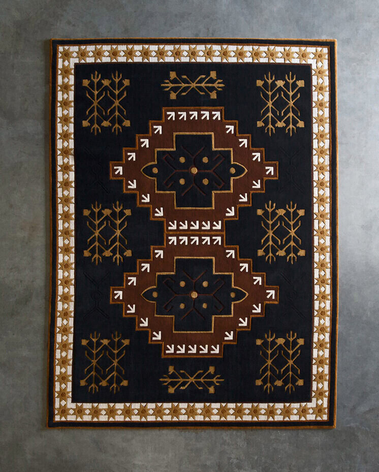 A luxury designer rug with geometric patterns in black, brown, and white on concrete.