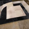 Luxury designer rug with geometric rectangles and curves in beige, brown, and black tones.