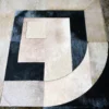 Close-up of a luxury designer rug with geometric beige, black, and grey hide patches.