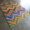 Luxury custom handmade hide rug with a vibrant zigzag pattern on gray concrete flooring.