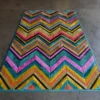Luxury custom designer rug with bold chevron pattern in vibrant hues on concrete floor.