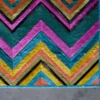 Luxury designer rug with colorful chevron pattern and furry texture on concrete floor.