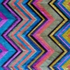 Close-up of a designer rug with a vibrant zigzag, handmade hide and silk, in blue, pink, yellow, gray, and purple.