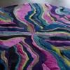 Luxury designer round rug with wavy pink, blue, green, purple, and black stripes.