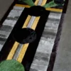 Luxury designer rug with geometric circles and stripes in green, black, yellow, and gray on concrete.