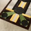 A luxury designer rug with geometric black, green, yellow, gray, and brown shapes on a light floor.