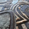 Detailed view of Mika Hide 29748 luxury designer rug, handmade patchwork of high end fur in gray, black, and beige geometric patterns.