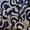 Luxury designer rug with swirling navy, beige, and cream mosaic shapes and purple accents.