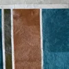 Luxury designer rug with rectangular brown, blue, and green hide patches in vertical stripes on gray.