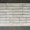 Luxury designer rug, rectangular and cream, with textured brick panels on gray floor.
