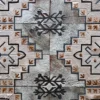 Close-up of designer Winterlude Hide 26667, a luxury handmade hide rug with geometric and floral motifs on grey textured material.