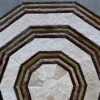 Luxury designer rug with octagonal patchwork in beige, brown, green handmade hide on gray floor.