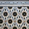 Close-up of Aubusson Hide 15998, a luxury designer rug with geometric circles, black florals, and blue-beige accents in high-end handmade hide.