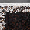 Luxury designer hide rug with white, brown, and black patchwork squares on gray floor.
