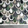 Close-up of a luxury designer rug with overlapping semicircles in green, gray, and beige on a plush handmade wool surface.