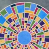 A luxury designer rug with a circular geometric mosaic in vibrant colors on gray.