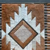 Luxury designer rug featuring a geometric diamond pattern in brown, gray, and white with textured handmade hide accents.