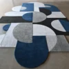 Luxury designer wool rug 15486 with geometric shapes on a sleek concrete floor.