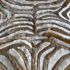 Close-up of designer handmade hide rug with symmetrical brown, white, and gray zebra pattern.