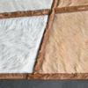 Close-up of a luxury designer hide rug in white, tan, and brown faux fur on a dark floor.