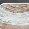 Close-up of the Drift Hide luxury designer rug with layered beige, cream, and tan fur patches.
