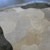 A close-up of a luxury custom designer rug with an abstract beige, gray, and cream pattern on a concrete floor.