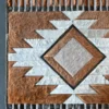 Luxury designer rug in geometric pattern, handmade from brown, white, and gray hide.