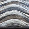 Close-up of luxury designer rug with chevron-patterned hide in gray, white, and blue.