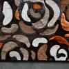 Close-up of a luxury designer rug with abstract swirls in earthy tones and a fur-like texture.