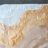 Close-up of luxury designer rug Drift Hide 27681, a handmade hide rug with flowing white, beige, and tan patterns.