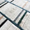 Close-up of a luxury handmade hide designer rug with a geometric grid pattern in beige, white, gray, and black.