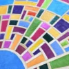 A vibrant designer rug with mosaic-style blue, green, and pink segments in a luxury handmade wool rug pattern.