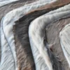 Close-up of a luxury designer rug: Flow Hide 29576 with wavy bands in brown, cream, and gray.