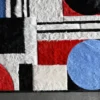 Luxury designer rug with textured fuzzy geometric shapes on a gray handmade hide rug.