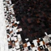 Luxury handmade hide rug with black, brown, and white cowhide patchwork pattern.