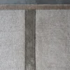 Luxury designer rug in beige silk and wool with intersecting stripes on concrete floor.