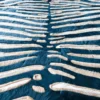 Close-up of luxury designer rug Zebra Hide 15581, featuring teal and cream stripes in a handmade hide pattern.