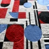 Luxury custom designer rug featuring red, blue, black and white geometric shapes on a plush textured hide surface.