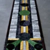 A luxury designer rug with geometric black, gray, yellow, and green patterns on concrete floor.