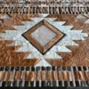 Close-up of Custom Hide 15069, a luxury designer rug with geometric fur pattern in brown, white, black, and gray.
