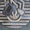 The Mika Hide 29748 is a luxury designer oval rug with abstract stripes on a gray concrete floor.