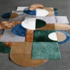 Luxury designer rug with geometric green, brown, and blue forms on a gray floor.