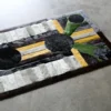 Luxury handmade designer rug featuring geometric patterns in black, white, yellow, and green on a concrete floor.