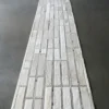 A luxury designer Beltway Hide 25131 handmade hide rug in white and light grey with a geometric grid pattern on a smooth grey floor.