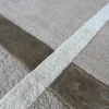 Close-up of a luxury custom designer rug with beige wool, silk, and geometric brown lines.