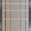 Luxury designer rug in beige silk and wool with a handmade grid, on a gray floor.
