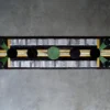 Luxury designer rug with black, green, and yellow geometric patterns on a textured gray background.