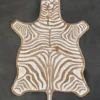 Luxury designer Zebra Hide 16332 flat handmade hide rug in tan and white on a dark gray floor.